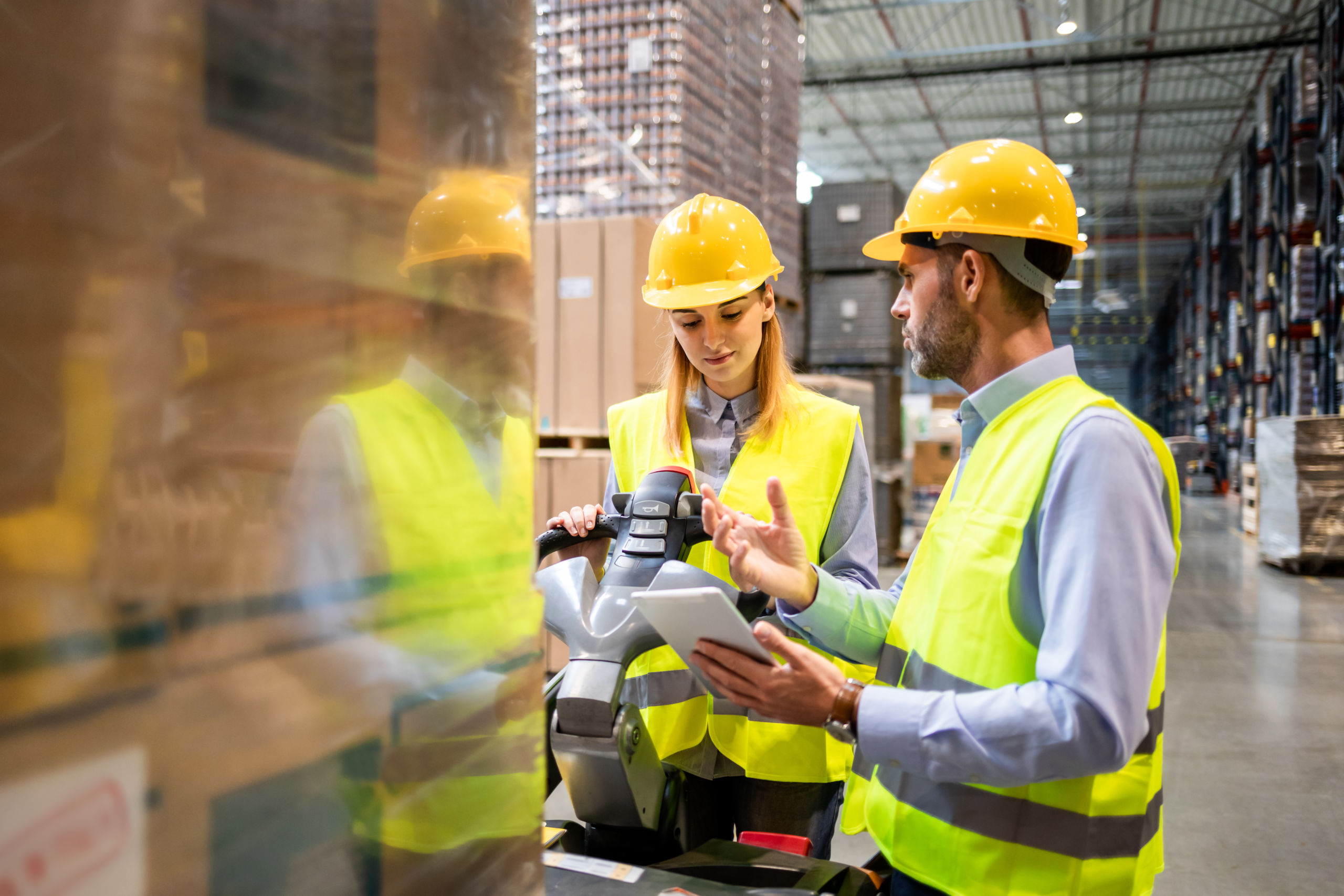 Female warehouse worker learns how to use forklift with instructor